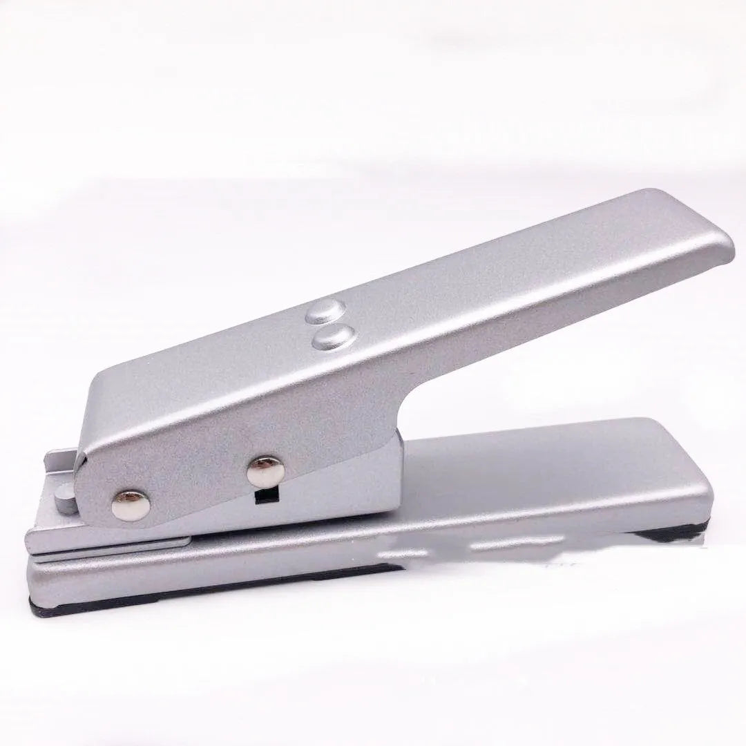Gold metal guitar pick card cutter on a flat surface showing the punch head and metallic finish