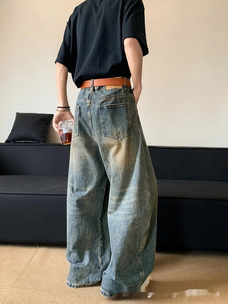 Man wearing retro blue distressed wide-leg denim jeans with a mid waist and zipper fly.