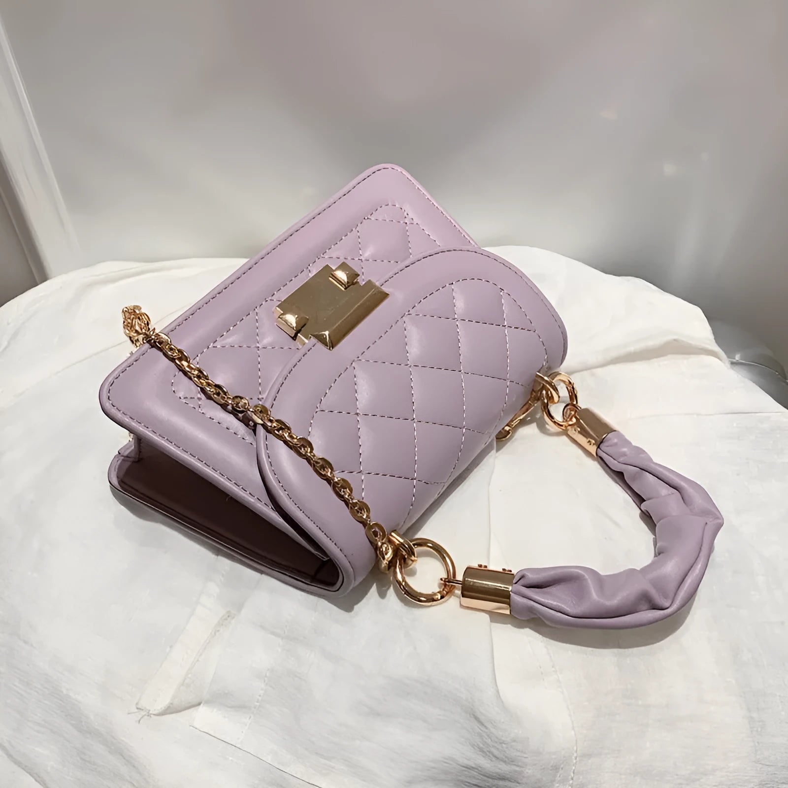 Purple rhombus-shaped small square shoulder bag with crossbody strap against neutral background