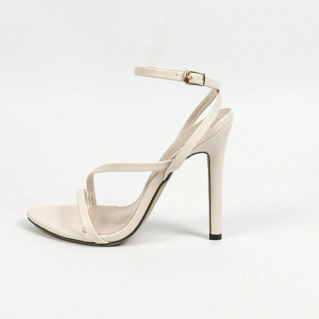 Gold women's high heel sandal with open round toe and cross ankle strap on a striped background.