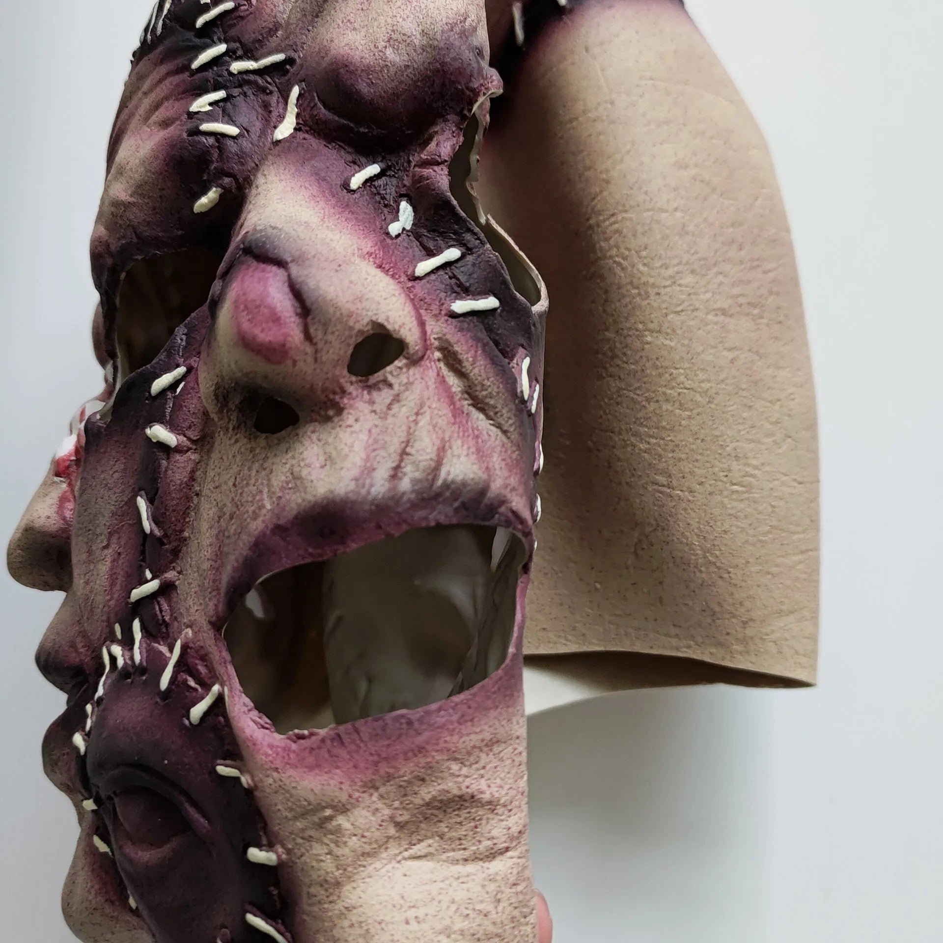 Three-sided grimace horror mask showing three distinct grotesque faces in natural latex