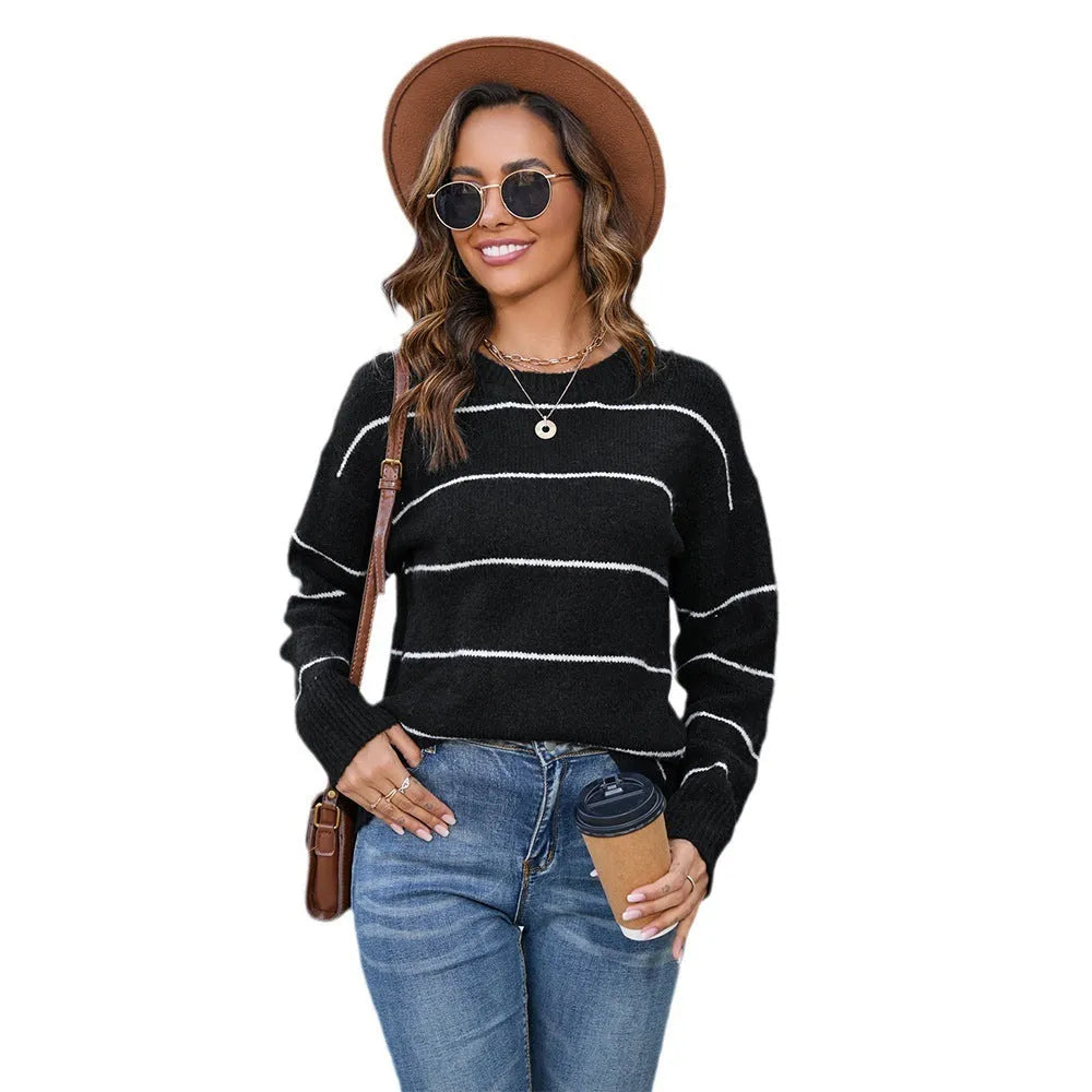 A woman wearing a black and white striped pullover sweater with a round neck and loose fit.