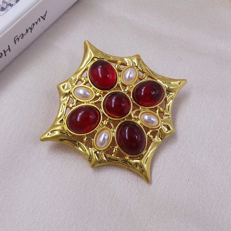 Close-up of a detailed baroque cross brooch with crystal accents on a zinc alloy base.