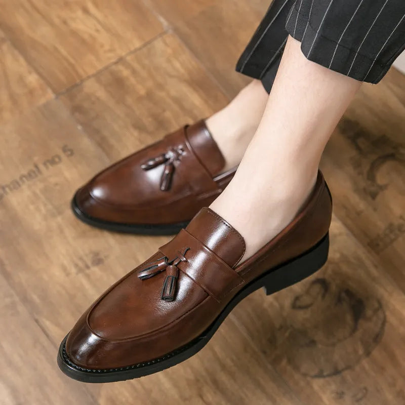 Men's black slip-on loafer with tassel detail and rubber sole on white background