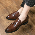 Men's black slip-on loafer with tassel detail and rubber sole on white background