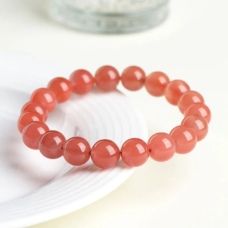 Natural cherry red agate bracelet with polished beads on a white background.