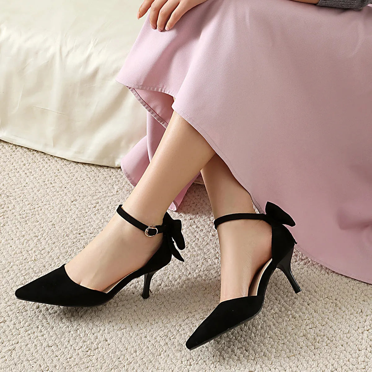 Women's black suede pointed-toe high heels with a stiletto heel and decorative bowknot at the ankle