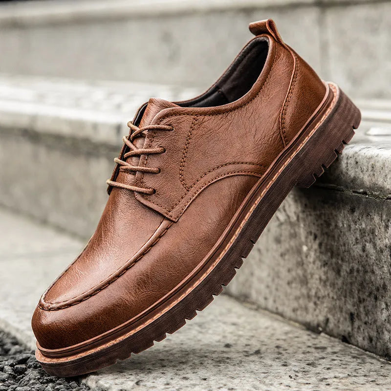 Men's black casual leather shoes with sewing line details and a round toe on a flat rubber sole.