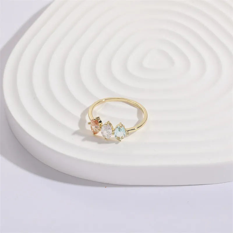 Geometric triangle birthstone ring with horse eye design and tricolour zircon stones on woman's hand