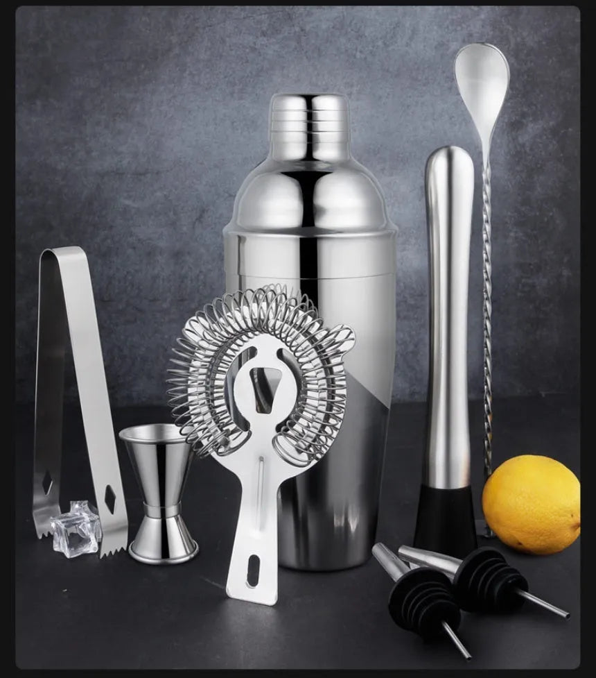 23-piece stainless steel cocktail set with shaker, jigger, strainer, and other bar tools on a wooden surface.