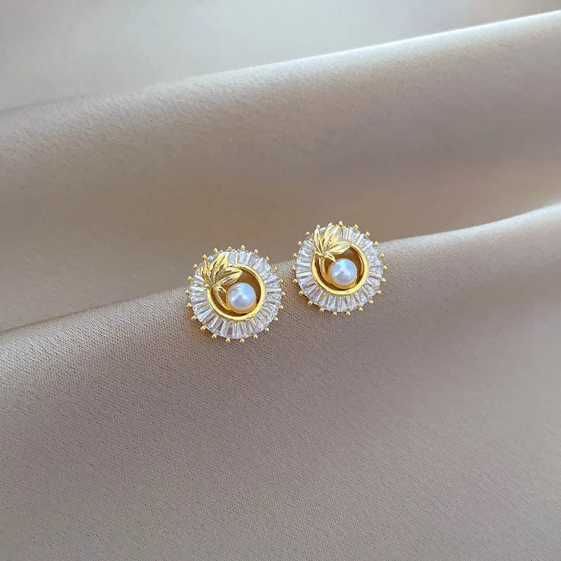 Square geometric necklace with diamond and leaf design alongside matching stud earrings