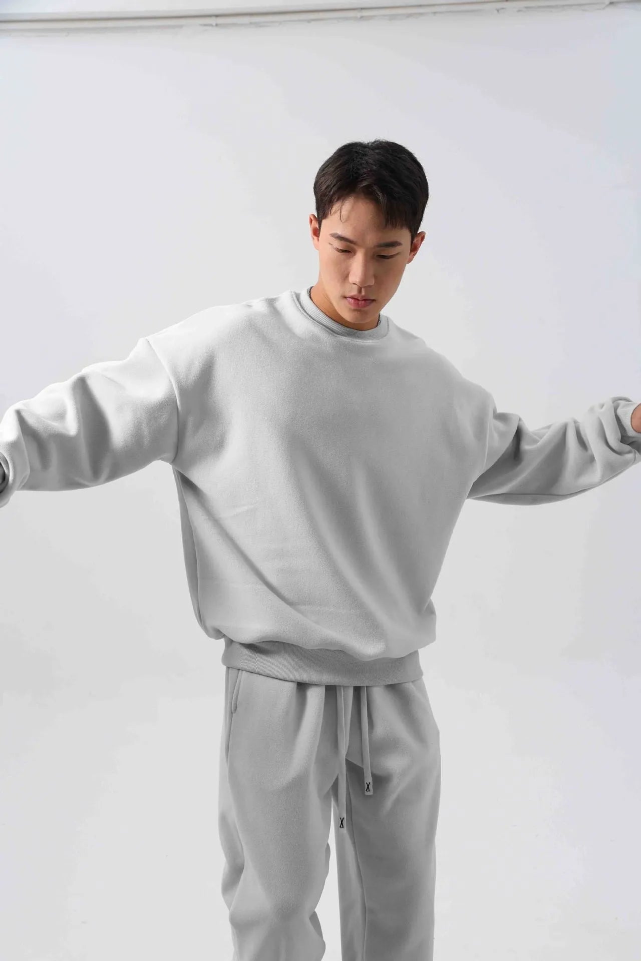 Men's black polar fleece sports suit with loose crew neck jacket and padded trousers on a hanger.