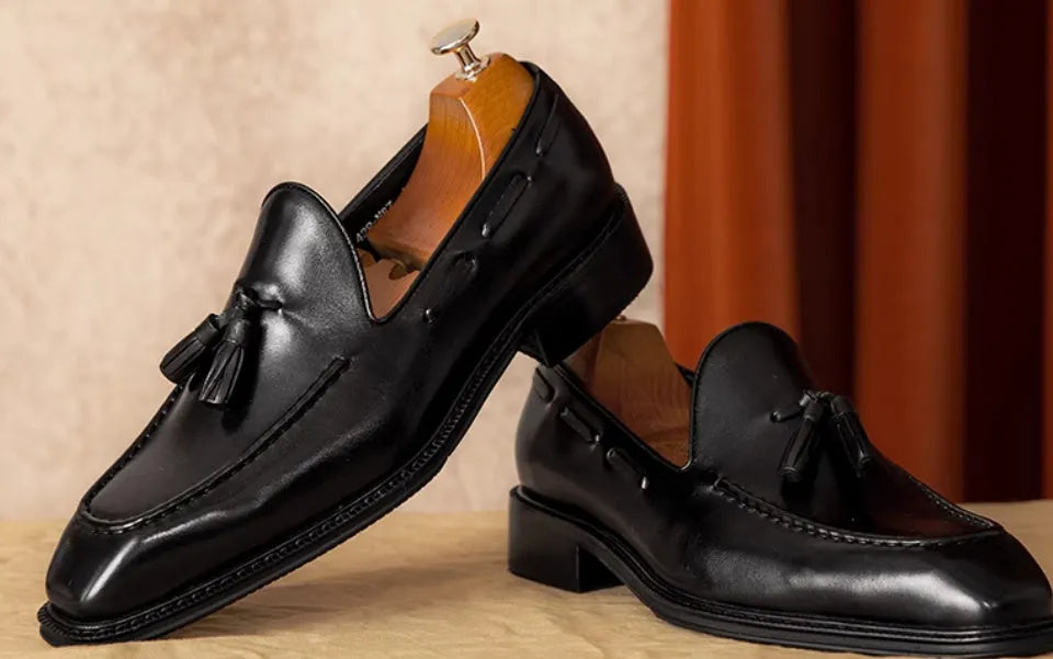 Men's black and brown genuine leather slip-on loafers with a pigskin lining, shown in multiple sizes.