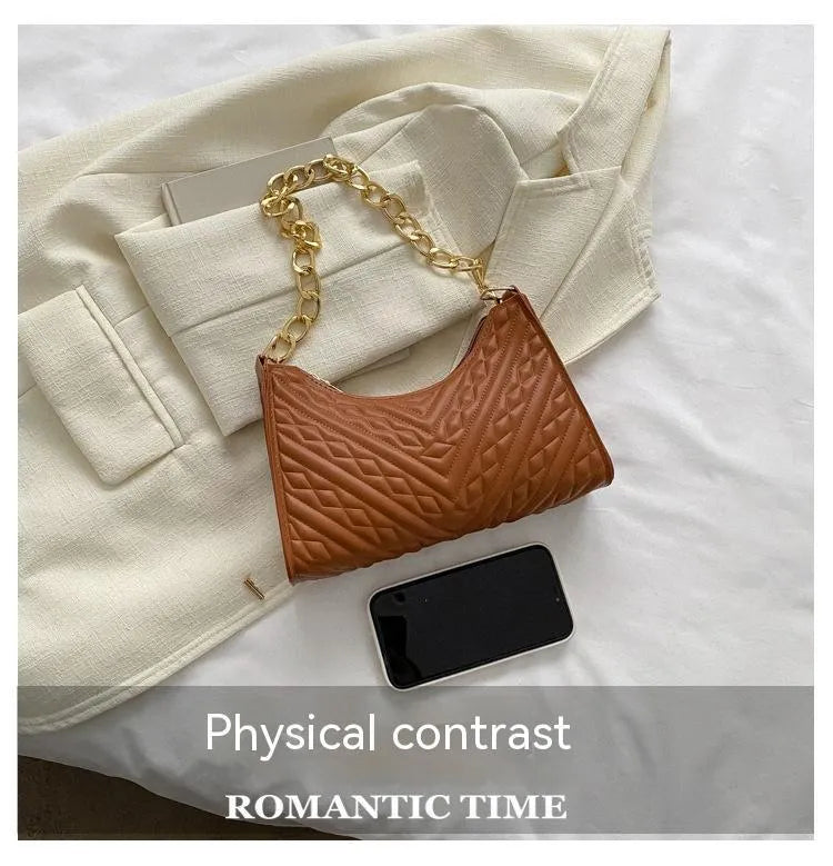 Vertical square brown PU shoulder bag with chain strap and soft handle on a table