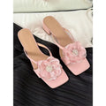 Women's cream-white satin sandals with a chunky heel and square toe on a light background.