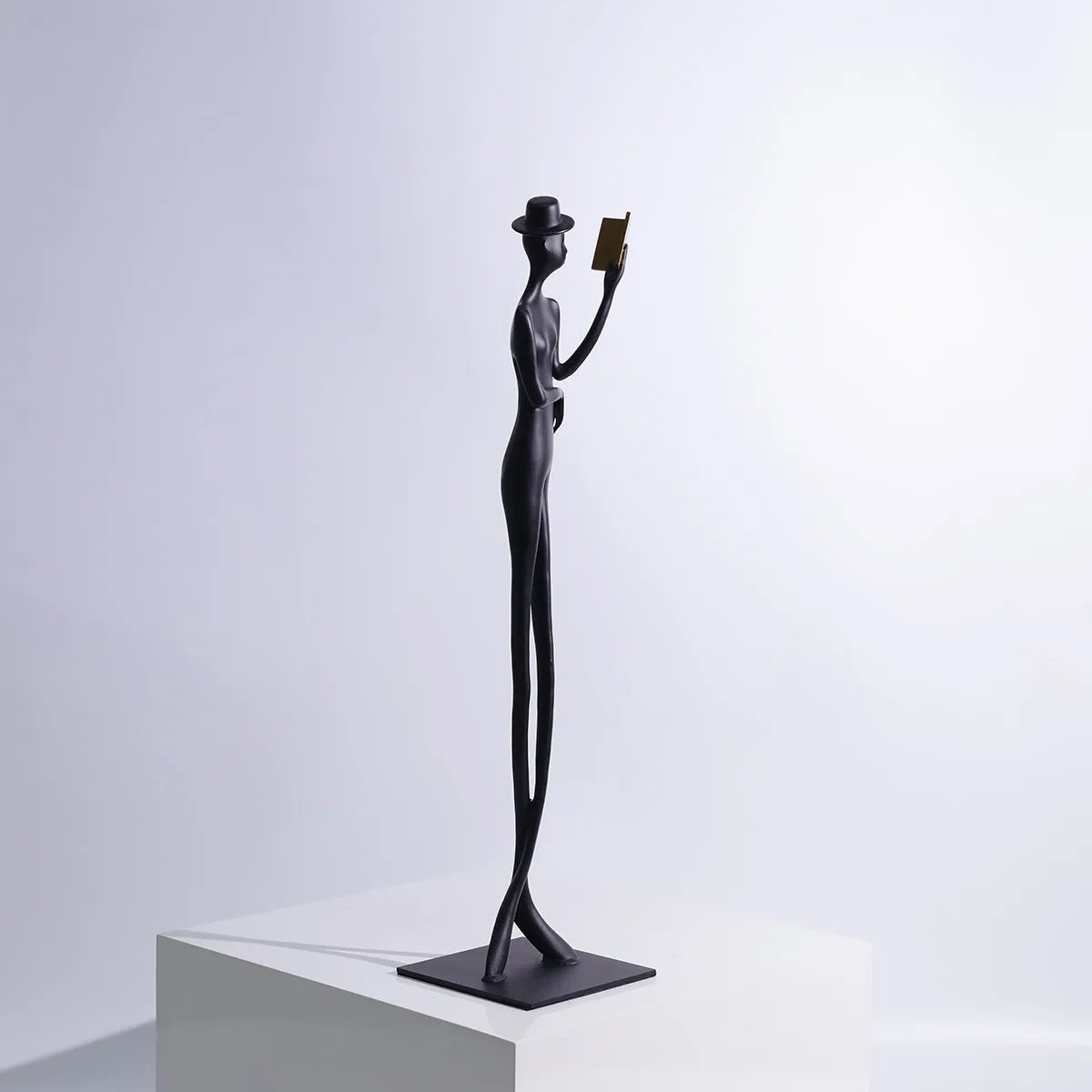 Black aluminium desktop sculpture of a woman reading, modern design.