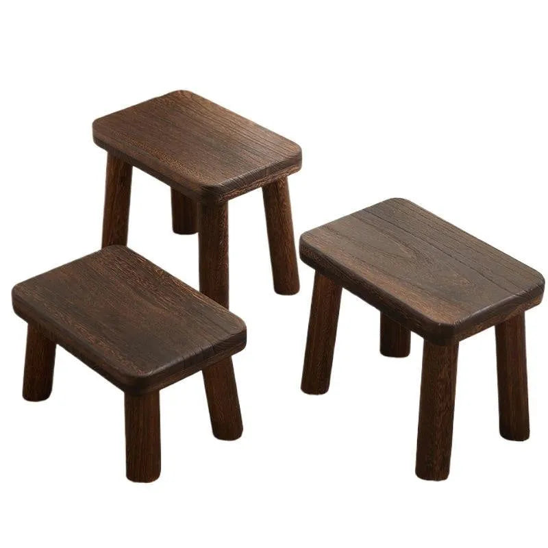 Solid wood distressed finish shoe changing stool with bracket legs in a living room setting.