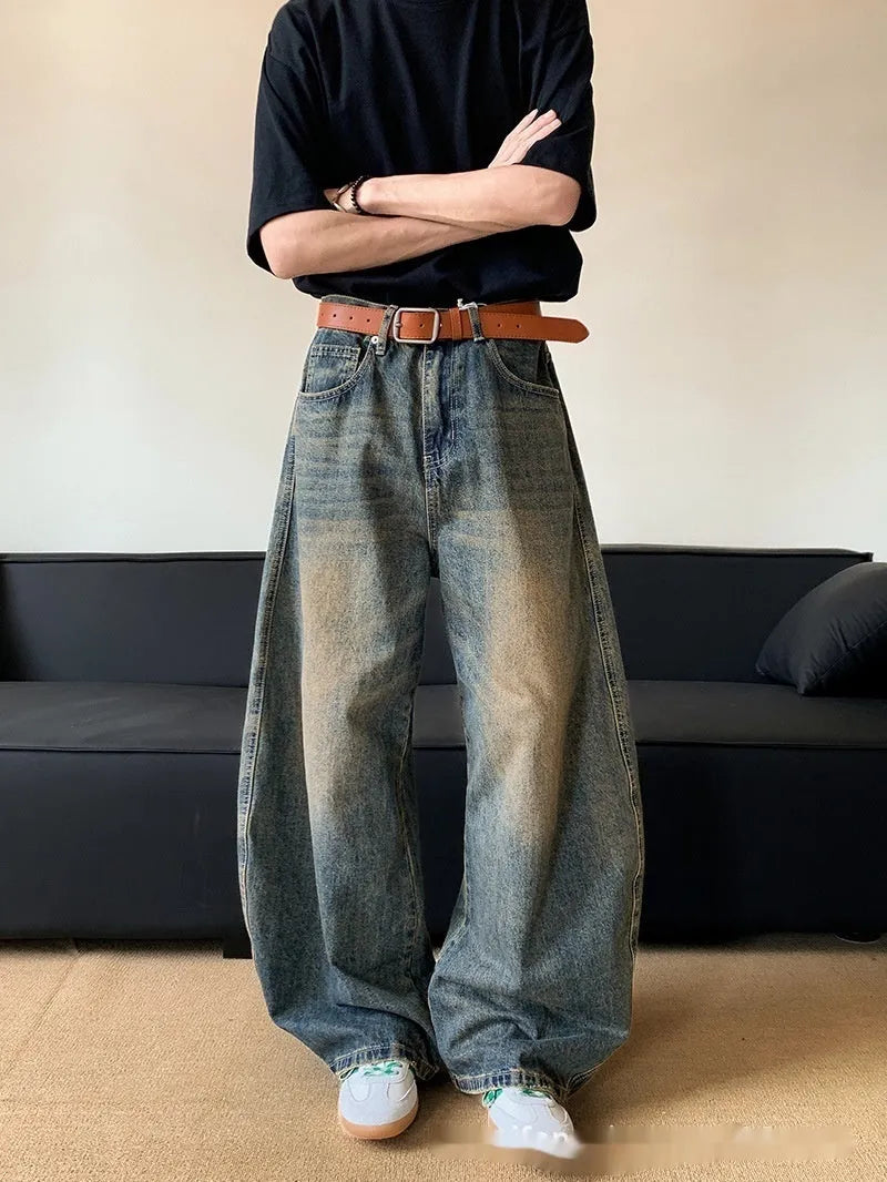 Man wearing retro blue distressed wide-leg denim jeans with a mid waist and zipper fly.