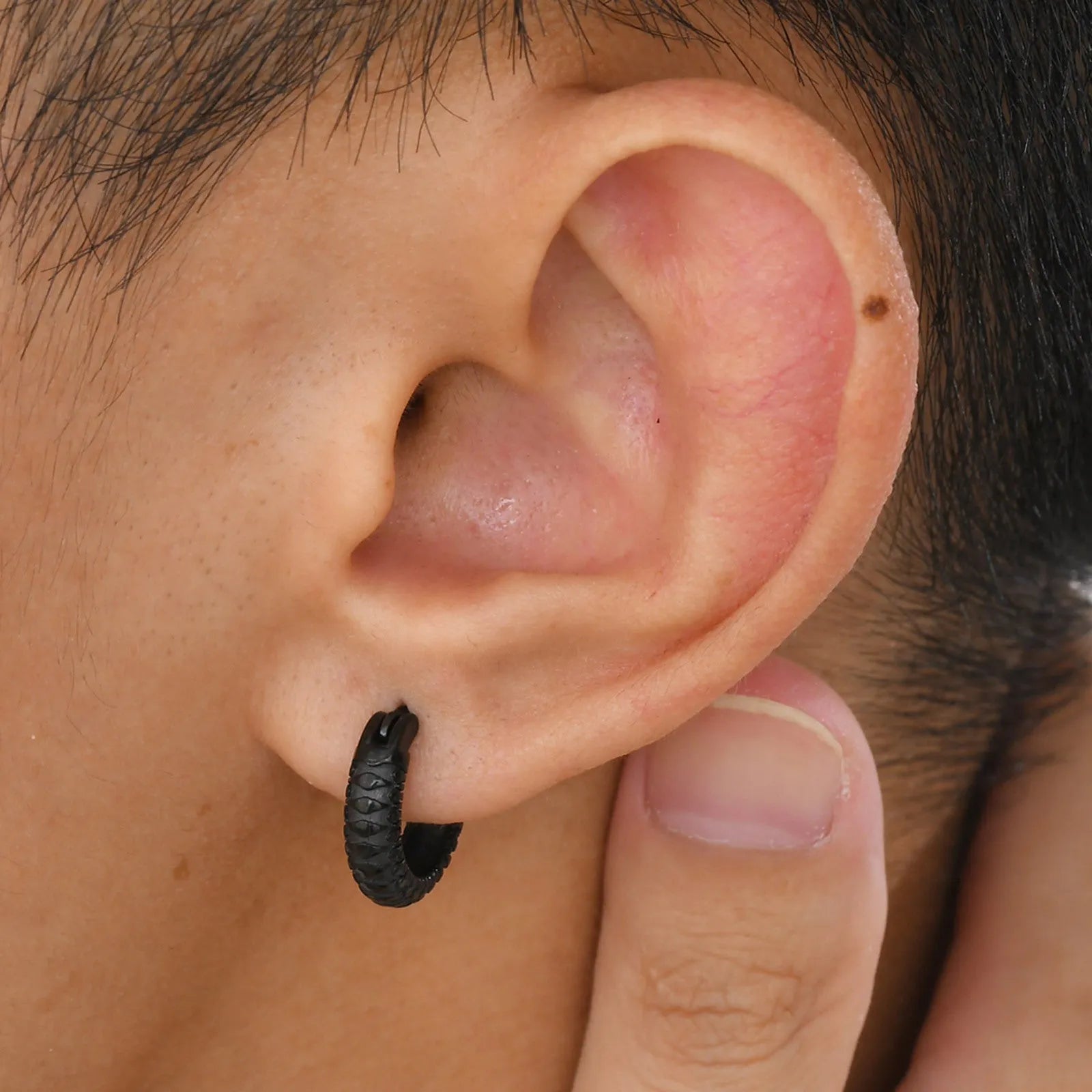 A pair of stainless steel earrings with a raised snake pattern texture in a black or gold finish.