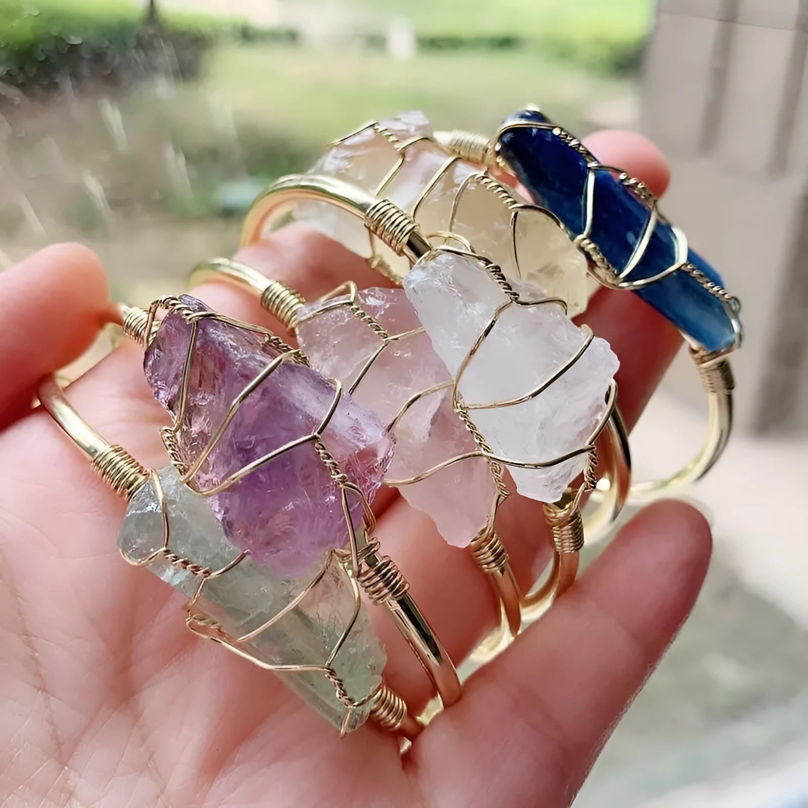 Natural rough crystal bracelet with geometric gold metal winding on a wrist.