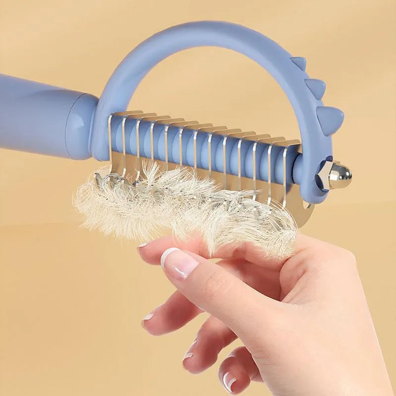 Blue dinosaur-shaped cat brush with self-cleaning button and double-sided bristles