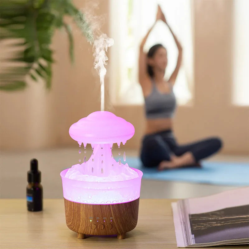 Wood grain white rain cloud shaped humidifier and essential oil diffuser with LED lights on a table.