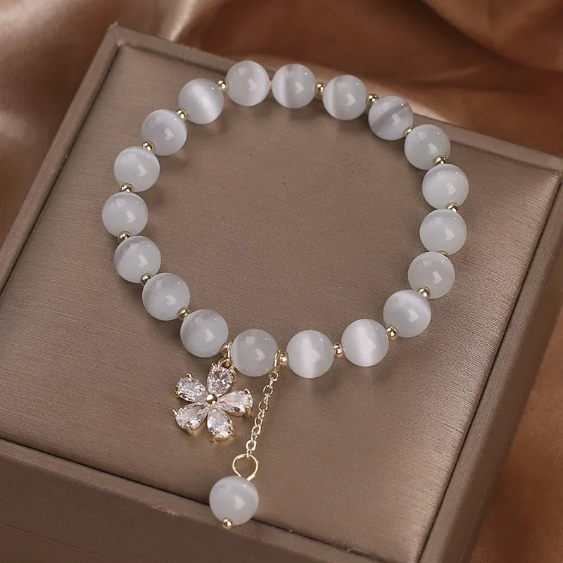 Women's white cat's eye bracelet with flower tassel and safety buckle pendant on wrist