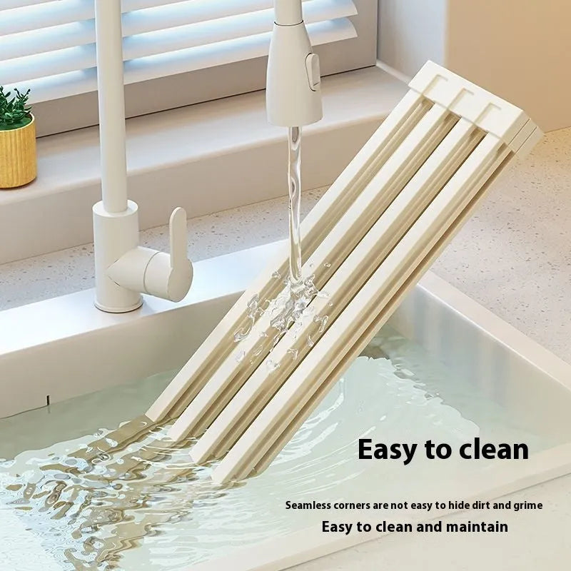 Milky white foldable stainless steel kitchen draining rack shown next to a sink.
