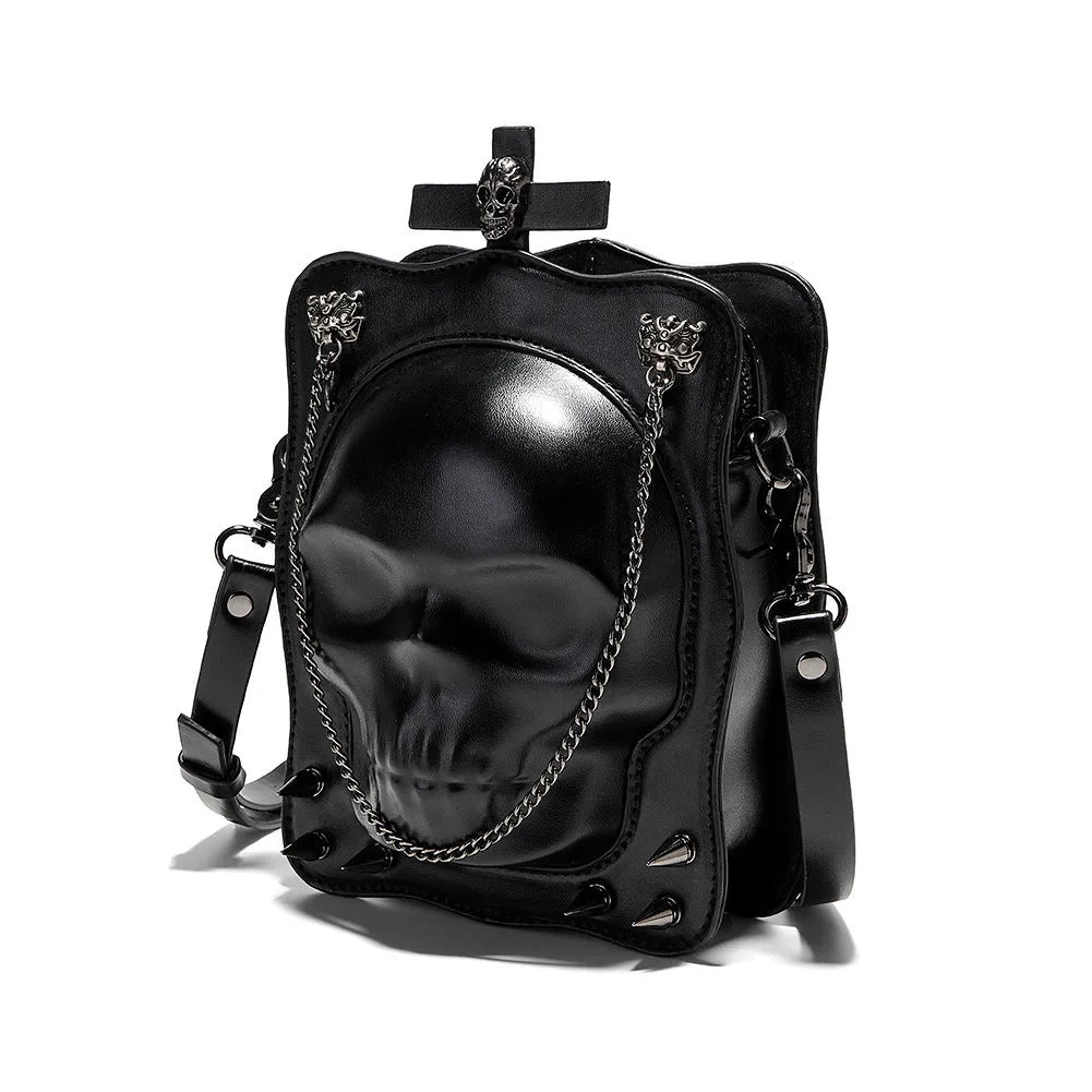 Black mini square crossbody bag with skull embossing, chain detail, and metal rivets on a vertical PU leather messenger bag.