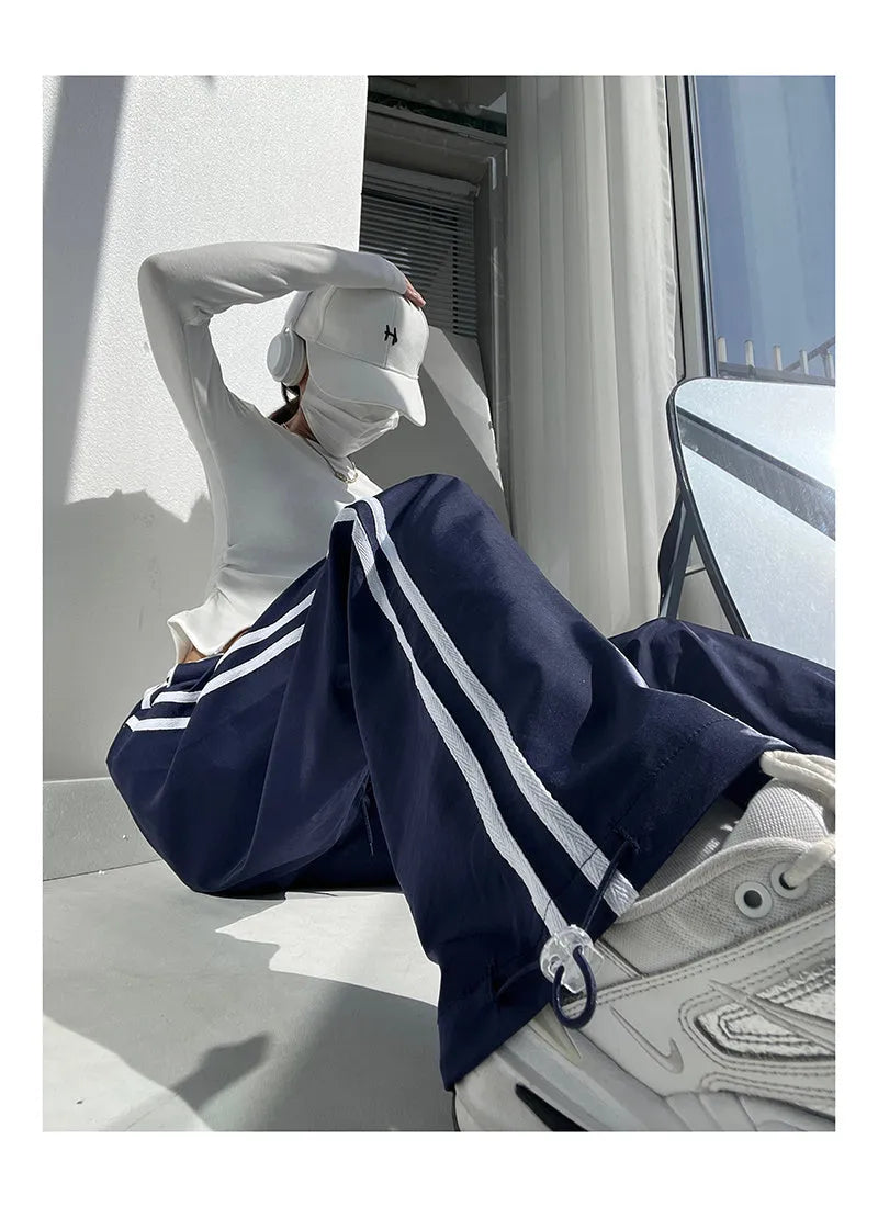 Women's navy blue loose straight-leg pants with white contrast ribbon parallel bars detail and low waist.