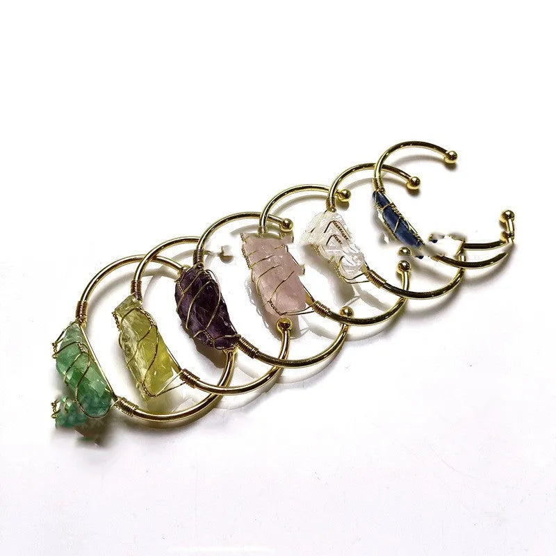 Natural rough crystal bracelet with geometric gold metal winding on a wrist.