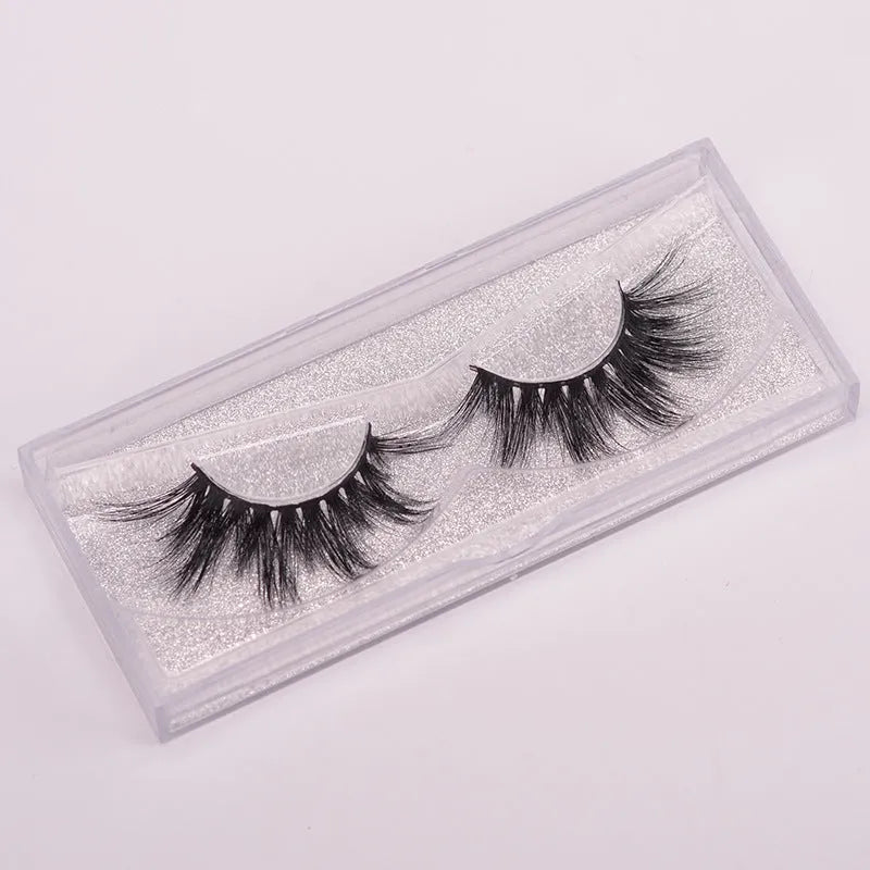 A pair of handcrafted 5D mink false eyelashes with applicator brush and storage case on a clean background.