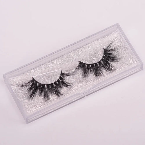 A pair of handcrafted 5D mink false eyelashes with applicator brush and storage case on a clean background.