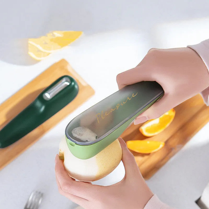Dark green vegetable peeler with storage tube, showing stainless steel blade and hanging hole on handle.