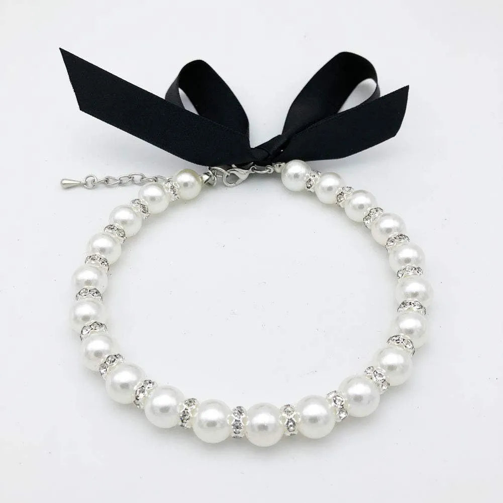 Adjustable blue pearl and rhinestone dog necklace collar with ribbon bow on a small dog.