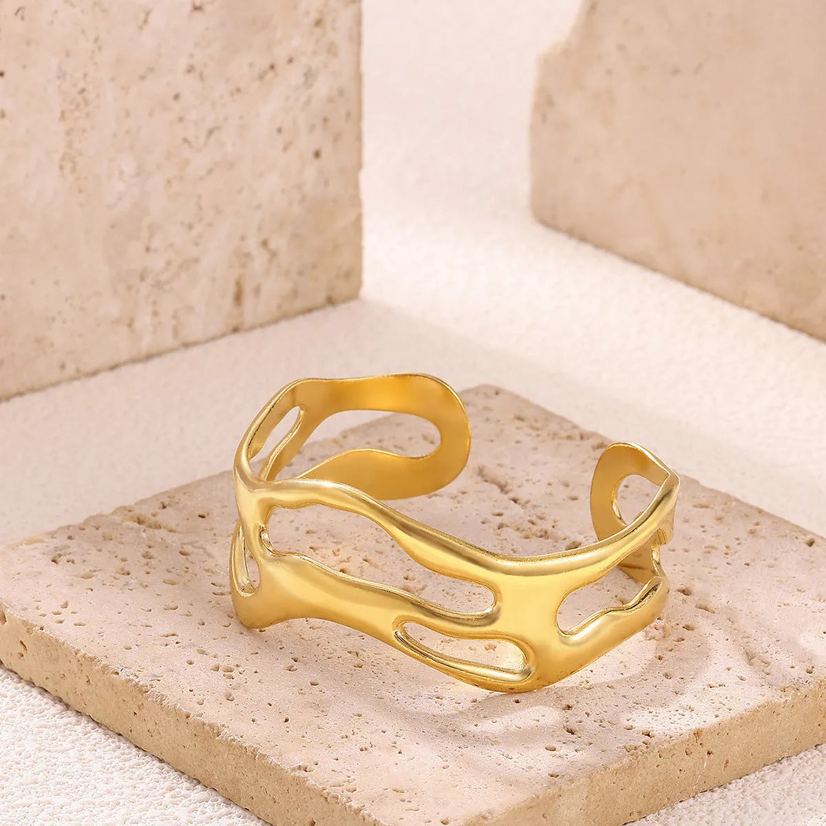 Simple irregular stainless steel gold-plated bracelet in silver finish on plain background