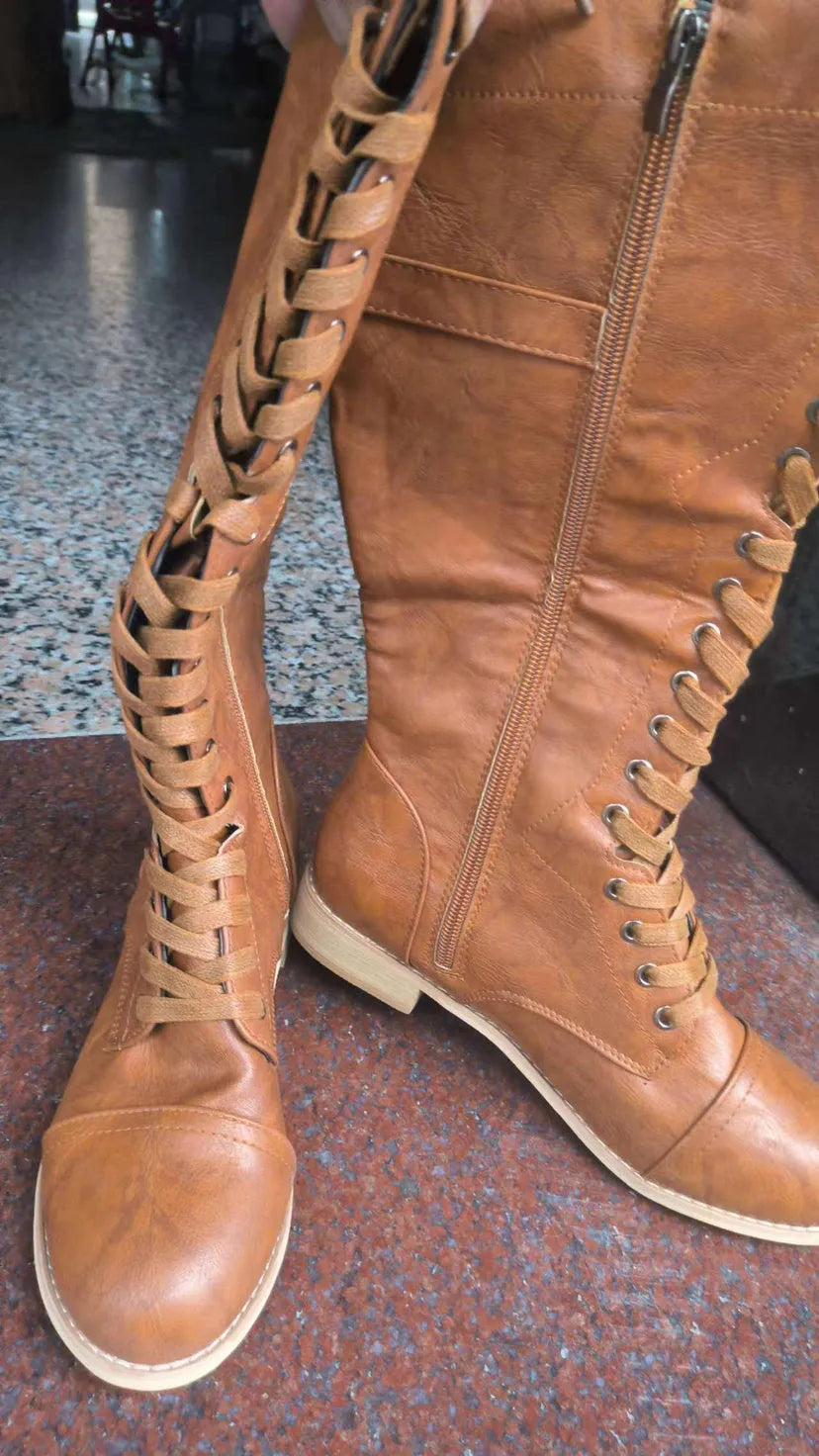 Women's black artificial PU knight boots with cross straps over the ankle.