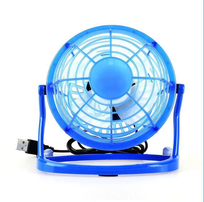 Compact black mini USB desk fan with adjustable tilt, placed next to a laptop.