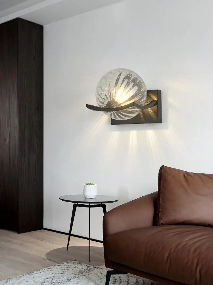 Modern minimalist black wall lamp with striped clear cover mounted beside a bed