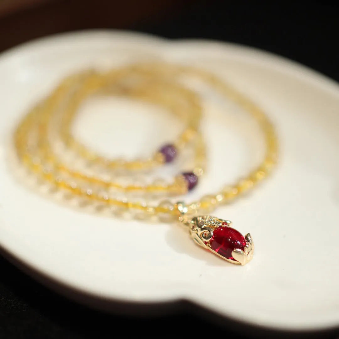 Natural quartz bracelet with three gold-coloured rings and hanging chopstick charms in a Chinese style.