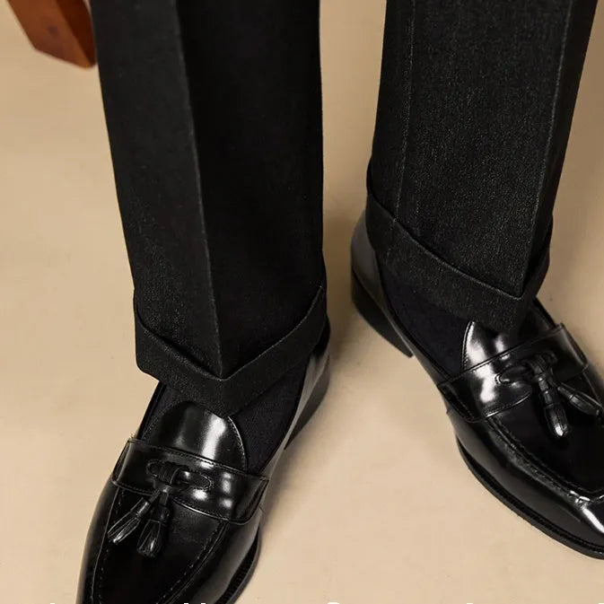 Men's black and brown tassel loafers with polished leather upper and rubber sole in British business casual style