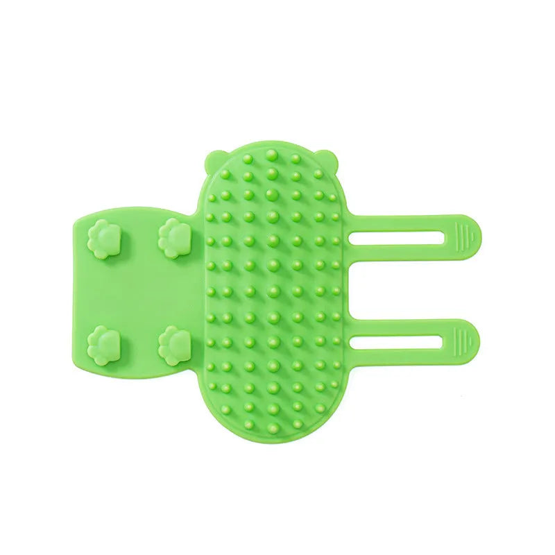 Silicone cat grooming comb with adjustable strap mounted on a table leg, shown in green colour.