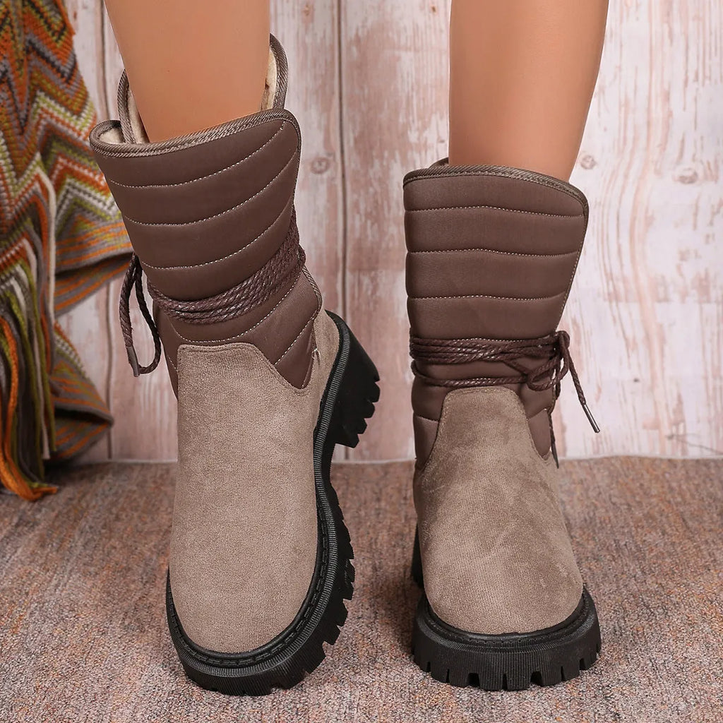 Women's black suede snow boots with chunky heel and lace-up design, shown on a foot.