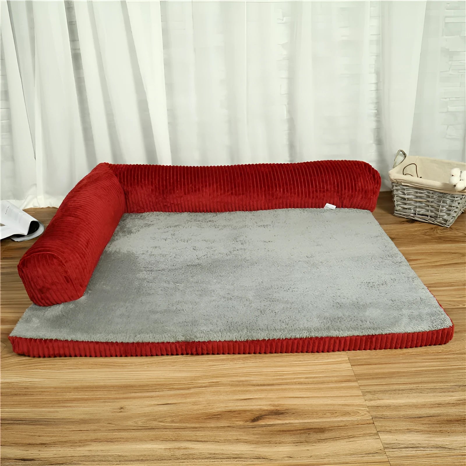 Grey corduroy dog sofa bed with raised sides on a wooden floor, showing its non-slip base.
