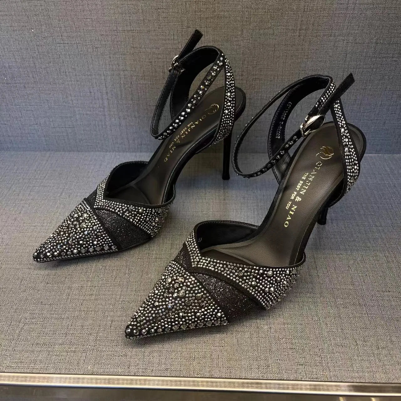 Women's silver high heel shoe with hollow stiletto heel, pointed toe, and bright red sole.
