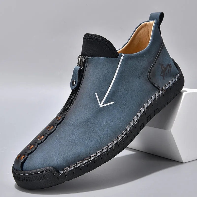 Men's black leather boots with a front zipper and round toe, showing hand-stitched sole detail.
