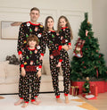 Family wearing matching red plaid Christmas pyjamas set, including adults, children, and a dog.
