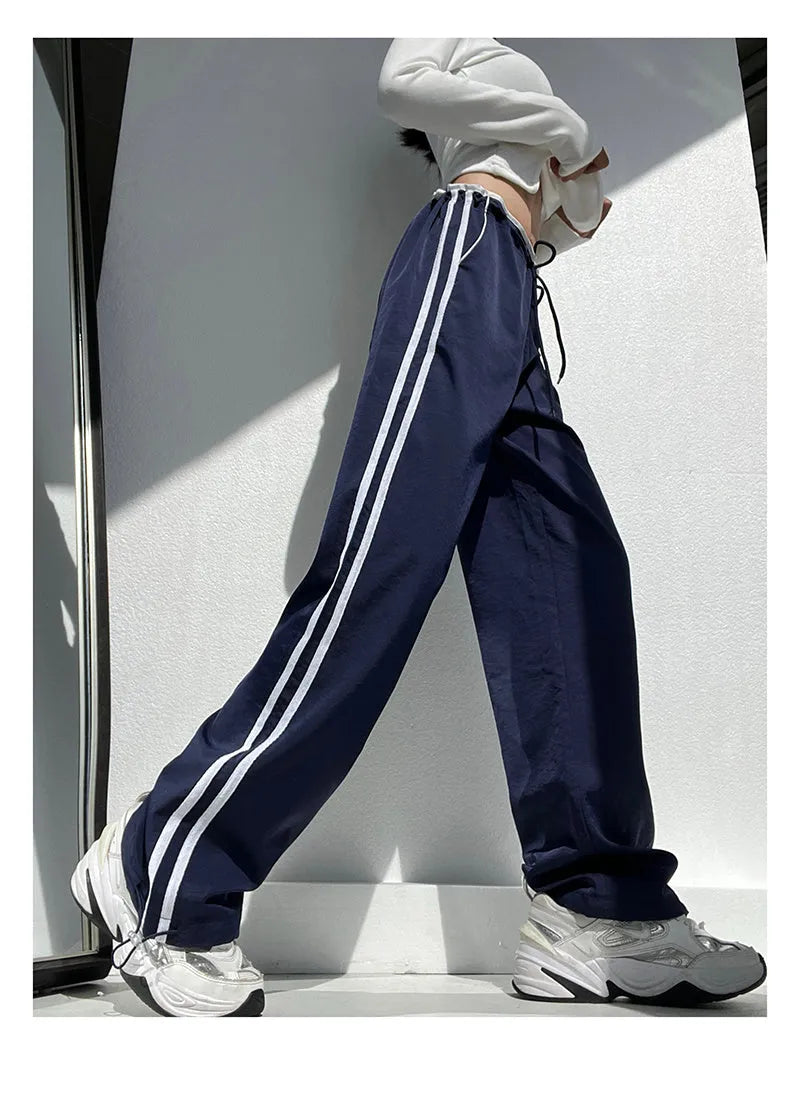 Women's navy blue loose straight-leg pants with white contrast ribbon parallel bars detail and low waist.