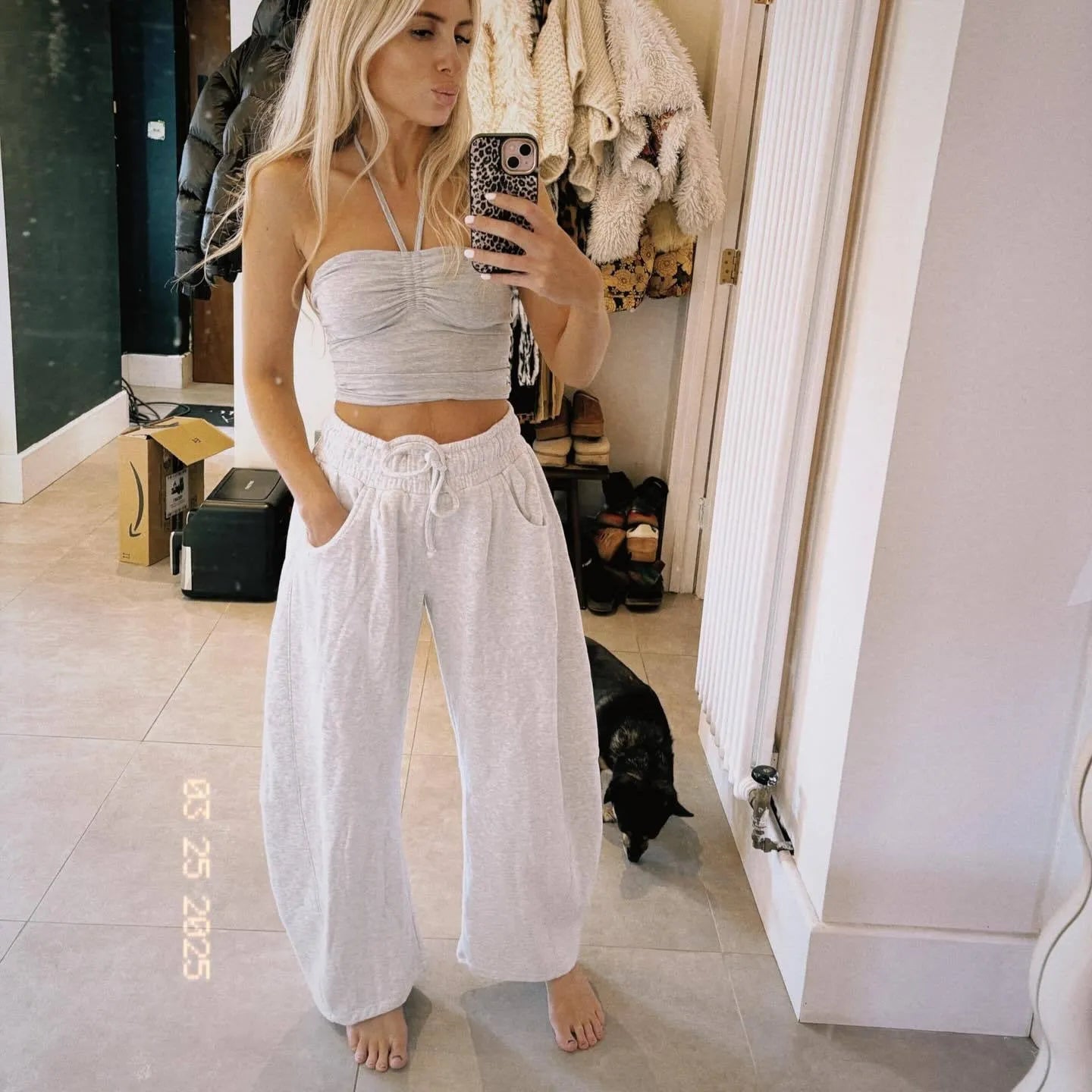 Women's loose grey cropped sweatpants with drawstring waist and side pockets on a hanger.