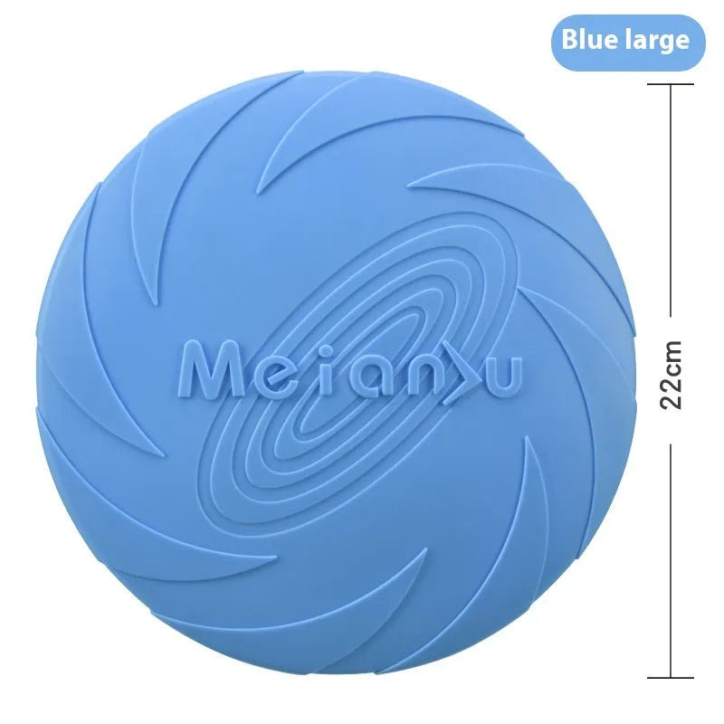 Soft rubber dog frisbee toy in blue, shown on grass for scale.